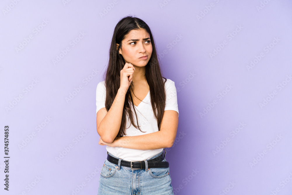 Young indian woman isolated on purple background confused, feels doubtful and unsure. Stock