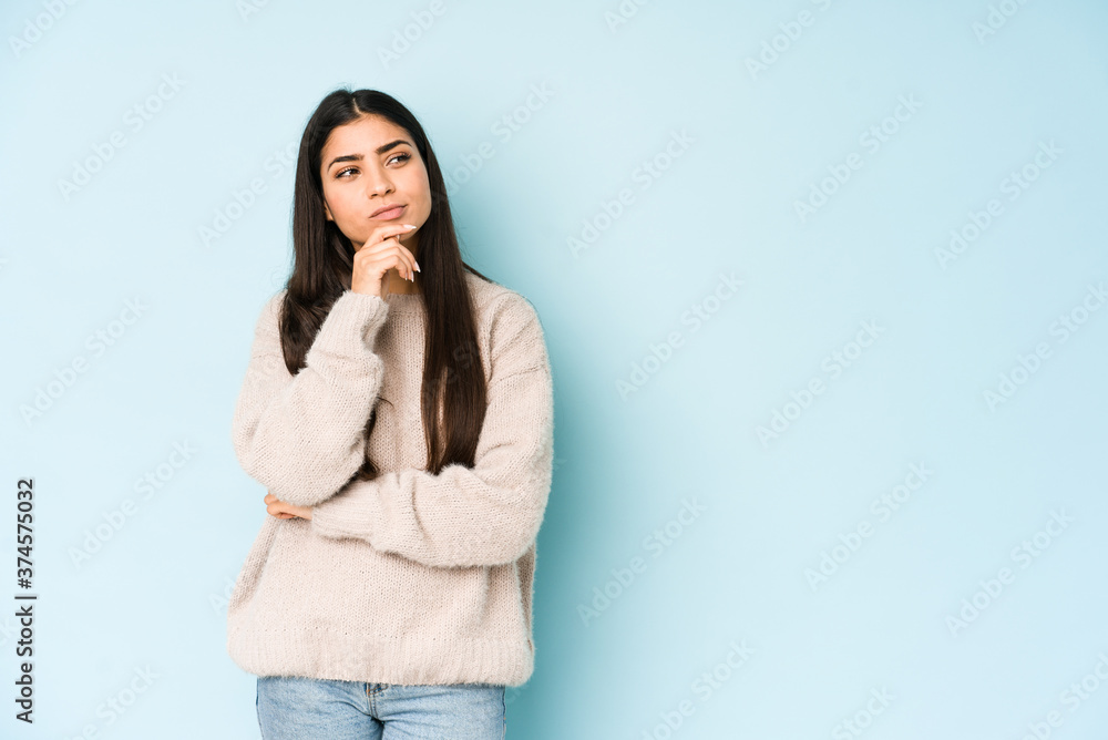 Young indian woman isolated on blue background suspicious, uncertain, examining you. Young indian woman isolated on blue background suspicious, uncertain, examining you.