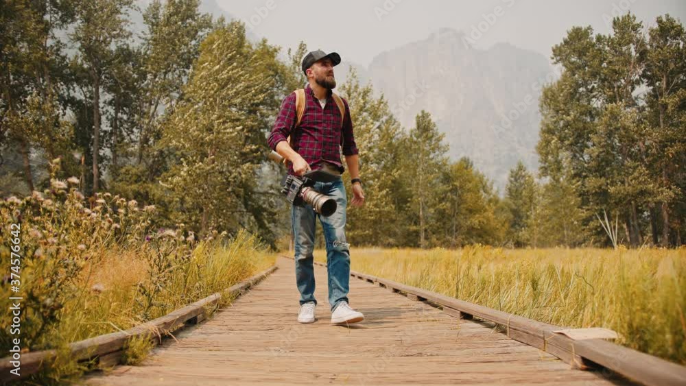 Travel videographer taking a steady shot of mountains through yellow grass with professional camera set in Yosemite National Park Travel videographer taking a steady shot of mountains through yellow grass with professional camera set in Yosemite National Park