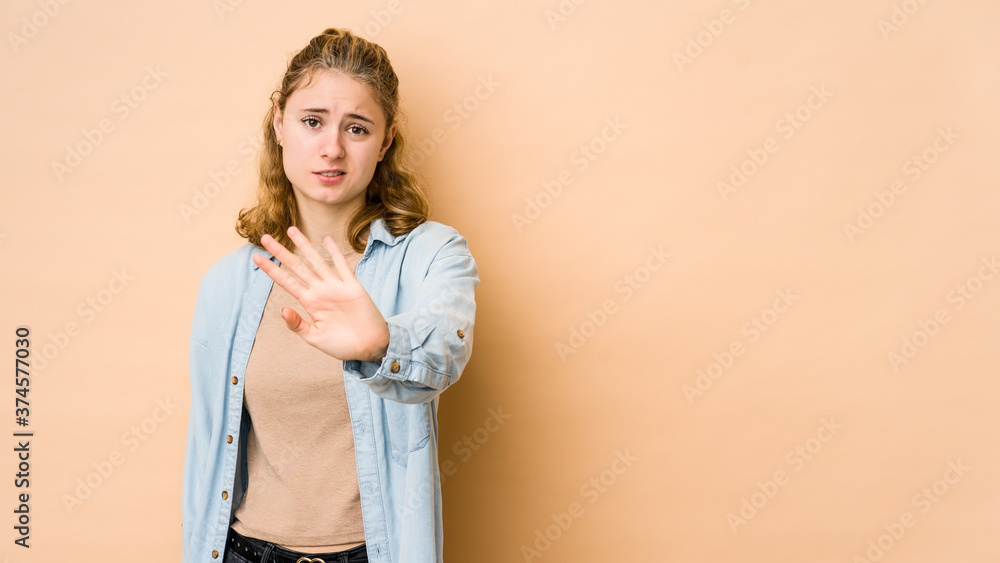 Obraz premium Young caucasian woman isolated on beige background rejecting someone showing a gesture of disgust.