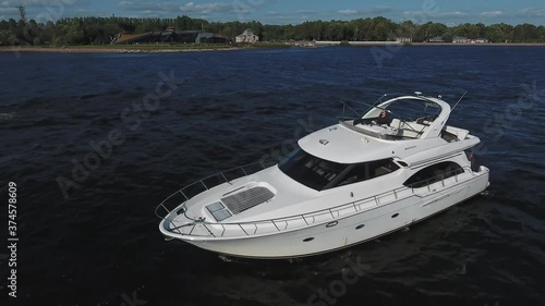 The man drive the yacht from the upper deck. View from a quadcopter