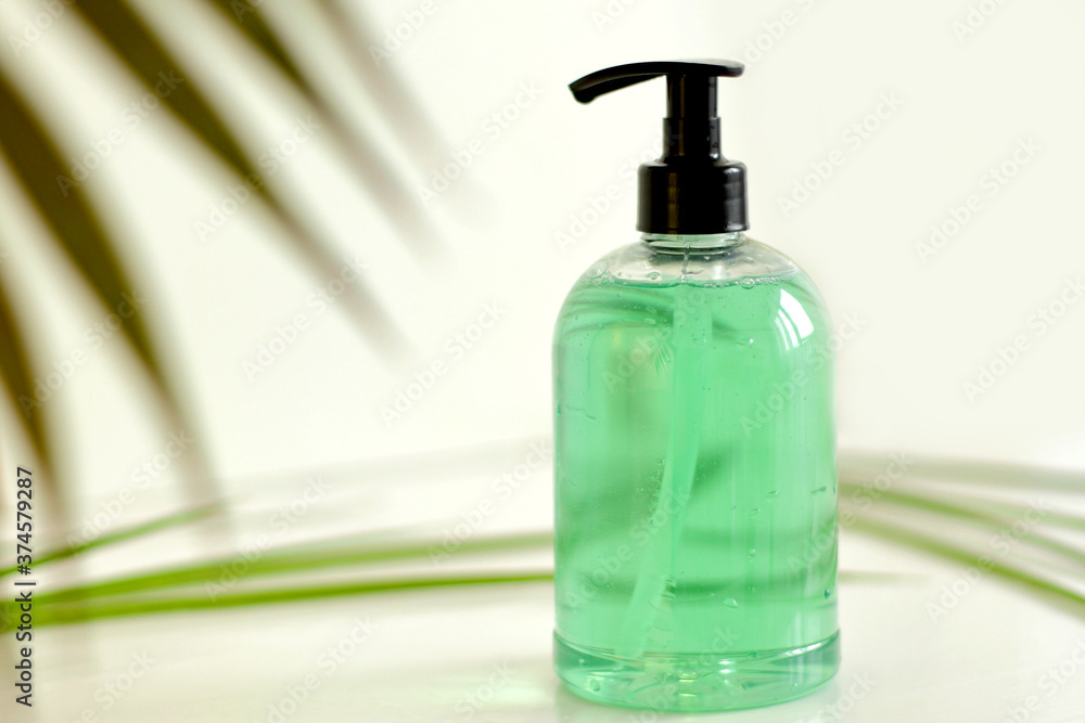 Plastic Bottle with green liquid soap on a white background with green leaves on background Plastic Bottle with green liquid soap on a white background with green leaves on background