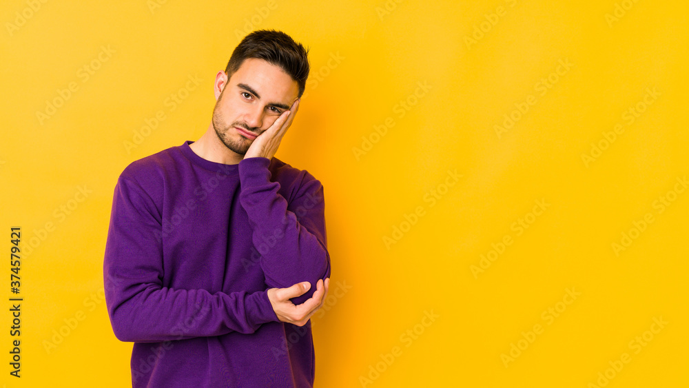 Young caucasian man isolated on yellow bakground who is bored, fatigued and need a relax day. Young caucasian man isolated on yellow bakground who is bored, fatigued and need a relax day.