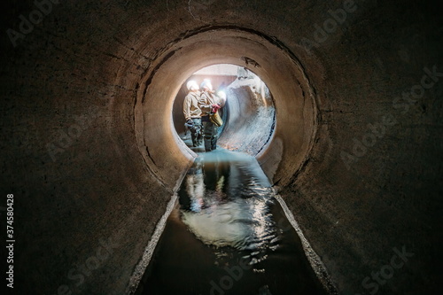 Fotografie Sewer tunnel workers examines sewer system damage and wastewater leakage