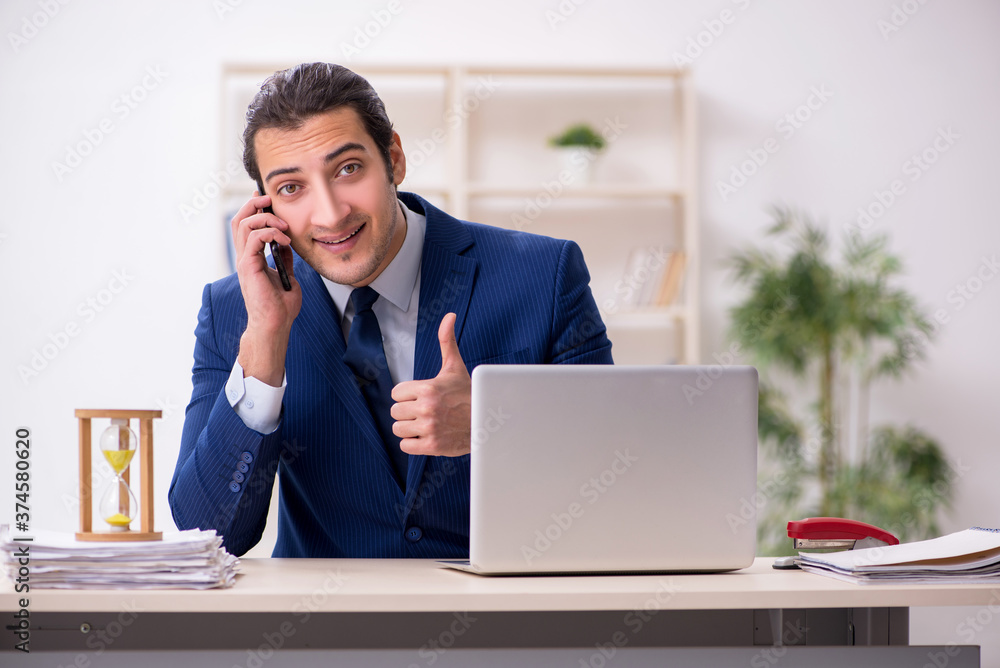 Young male employee in time management concept Young male employee in time management concept