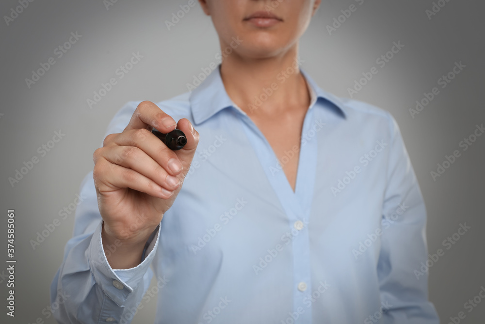 Woman with marker against grey background, focus on hand Woman with marker against grey background, focus on hand