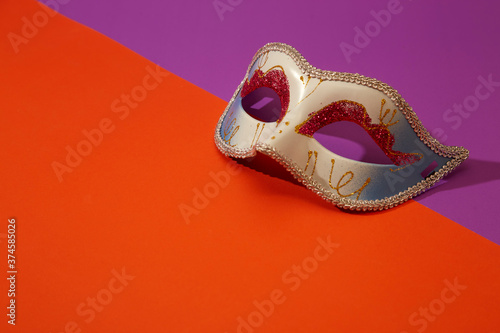 Venetian mask on bright orange and violet background