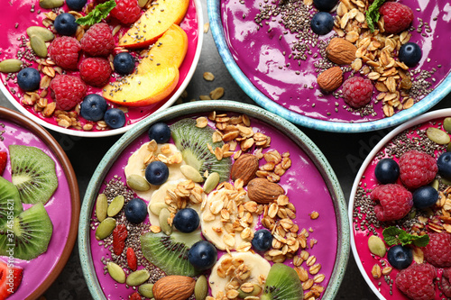 Delicious acai smoothie with toppings in bowls on table, flat lay