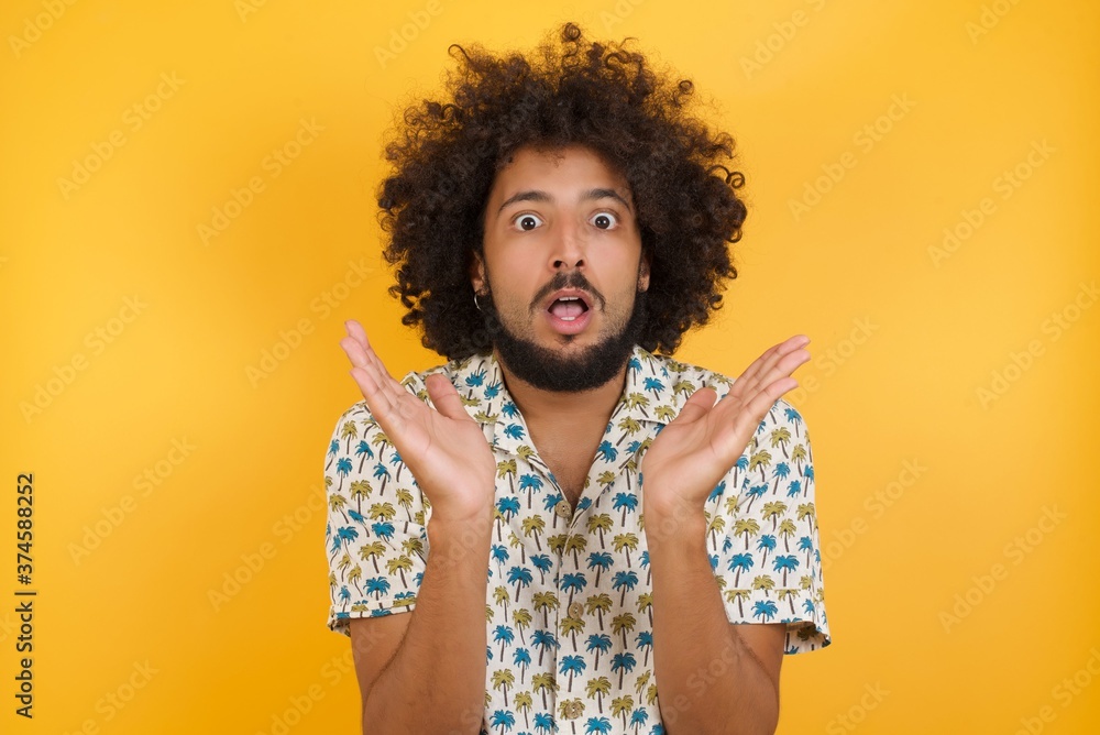 Surprised terrified Young man with afro hair Gestures with uncertainty, stares at camera, puzzled as doesn't know answer on tricky question, People, body language, emotions concept Surprised terrified Young man with afro hair Gestures with uncertainty, stares at camera, puzzled as doesn't know answer on tricky question, People, body language, emotions concept