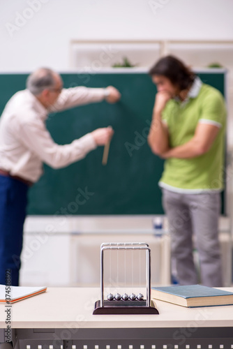 Фотография Old professor physicist and young student in the classroom