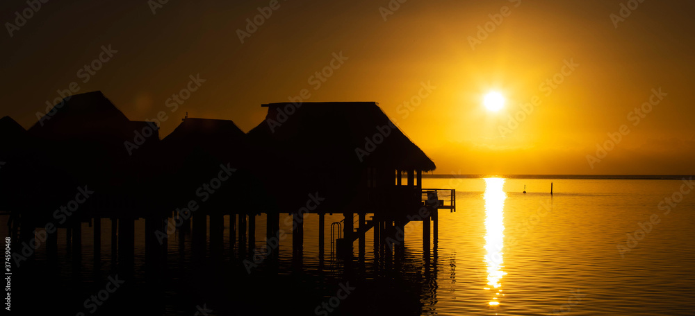 General view of overwater bungalows during beautiful sunrise with colorful orange sky