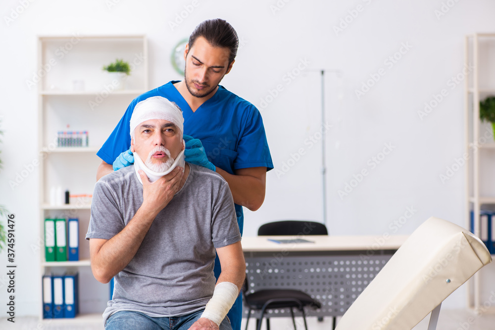 Fototapeta premium Young male doctor and old patient in first aid concept