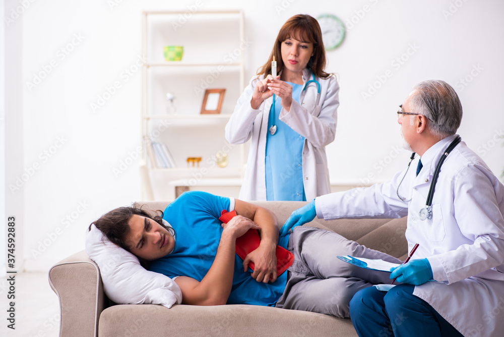 Fototapeta premium Two doctors visiting sick young man at home
