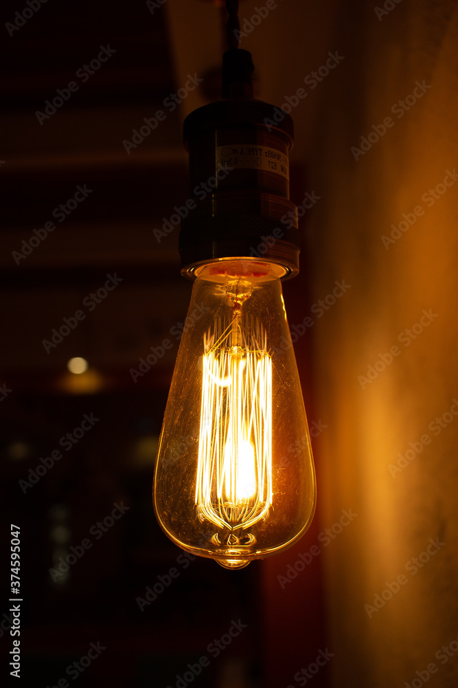 Golden shining antique Edison style bulb in the dark. Lighting decor concept. Vintage light bulb