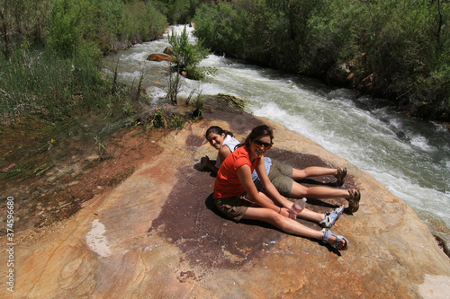 Two young women rest by Tapeats Creek on multiday backpacking trip in Grand Canyon National Park, Arizona in summer. photo