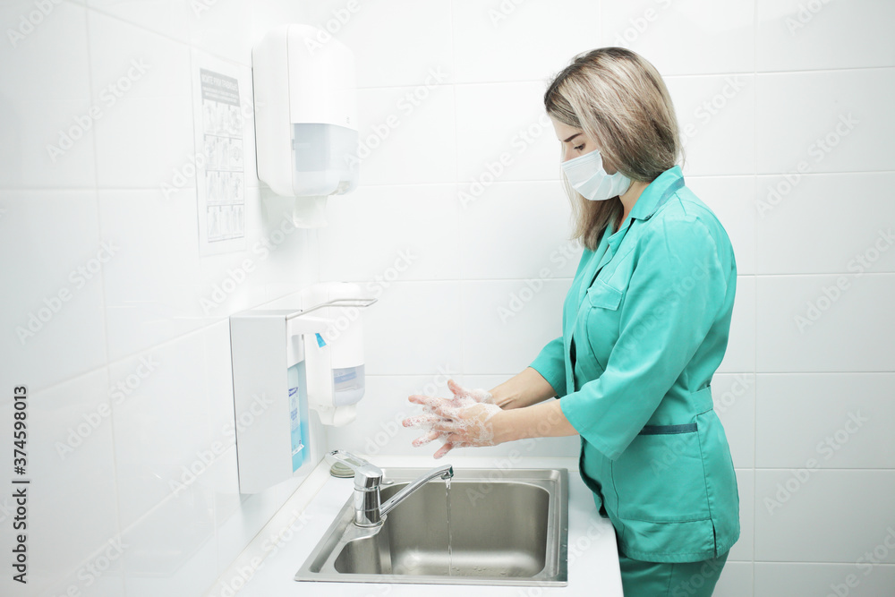 A woman doctor in protective mask washes hands thoroughly in hospital