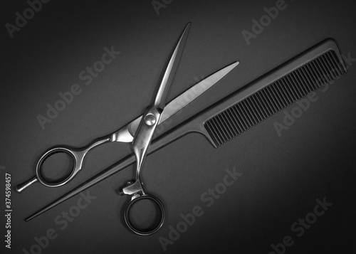 Scissors and comb. Hairdresser Shears for haircut on black background. Beauty salon equipment.