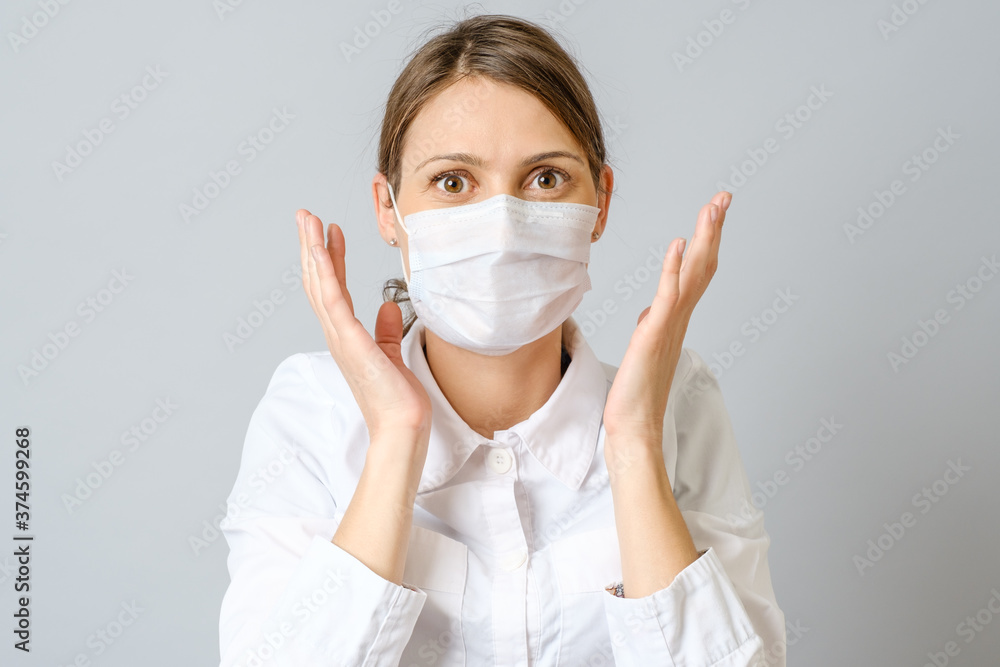 Surprised doctor in mask isolated on gray