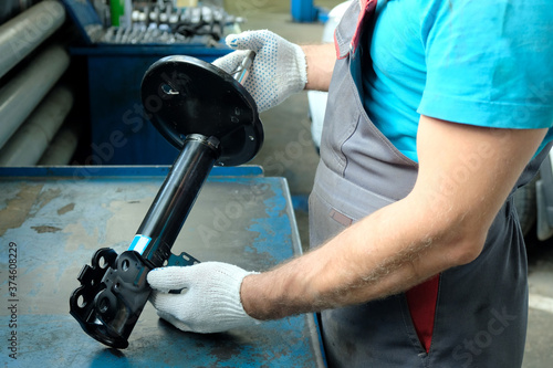 In the hands of a car mechanic, a new shock absorber strut. Repair and maintenance of the car in the service center. The technical condition of the shock absorber is checked before installation.