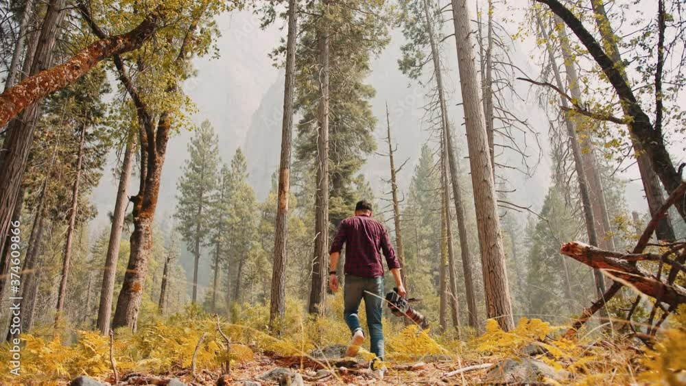 Photographer with professional camera set walking through autumn forest in Yosemite National Park Photographer with professional camera set walking through autumn forest in Yosemite National Park