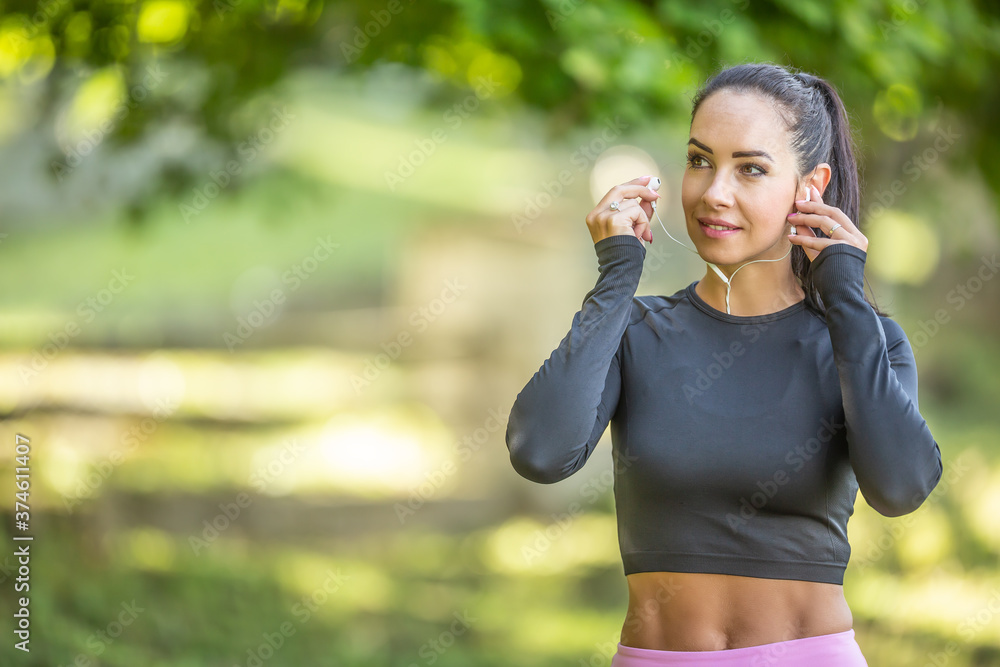 Young sporty woman runner with a nice smile before running with earphones listens to motivational music Young sporty woman runner with a nice smile before running with earphones listens to motivational music