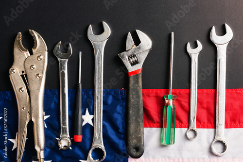 Labor day concept, Top view flat lay of different kinds wrenches with American flag on black. First Monday in September, creation of labor movement and dedicated to social of the American worker