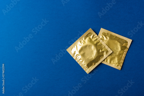 World sexual health or Aids day, Top view flat lay condom in wrapper pack, studio shot isolated on a dark blue background, Safe sex and reproductive health concept