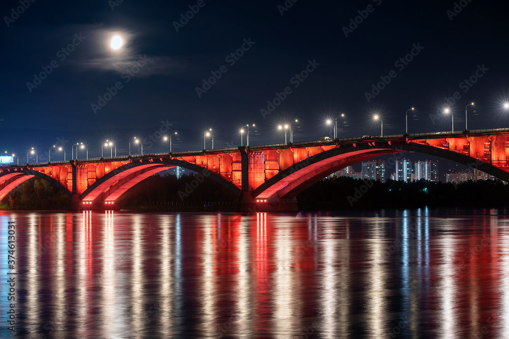 Krasnoyarsk, Russia. Night view of Krasnoyarsk Communal bridge with red backlight and Yenisey river.