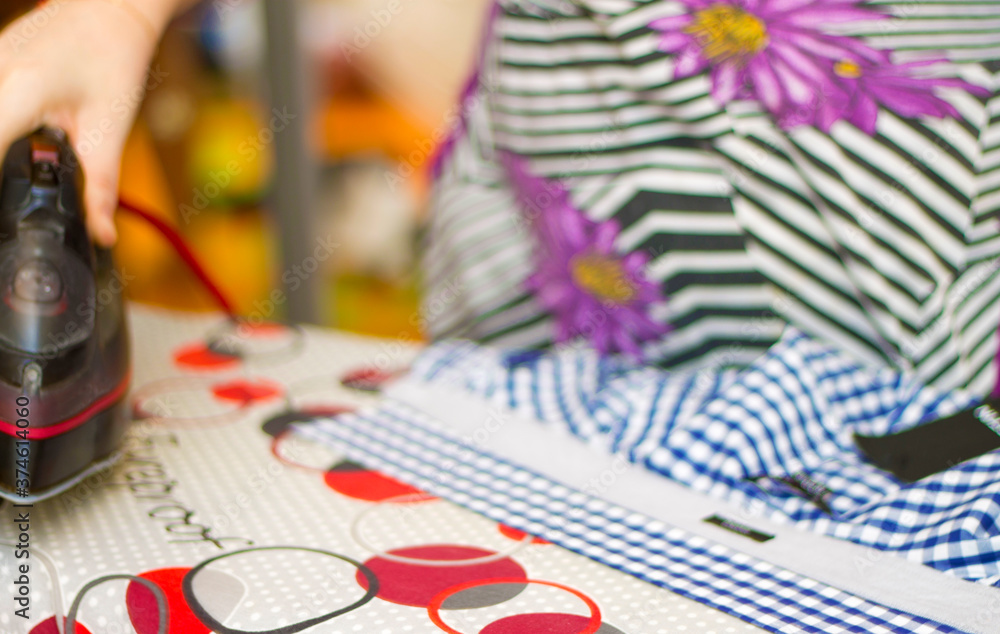 Naklejka premium Housewife ironing a casual clothes on the ironing board closeup