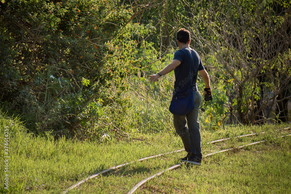Unrecognizable boy walks on the abandoned train tracks. Concept of lifestyle.