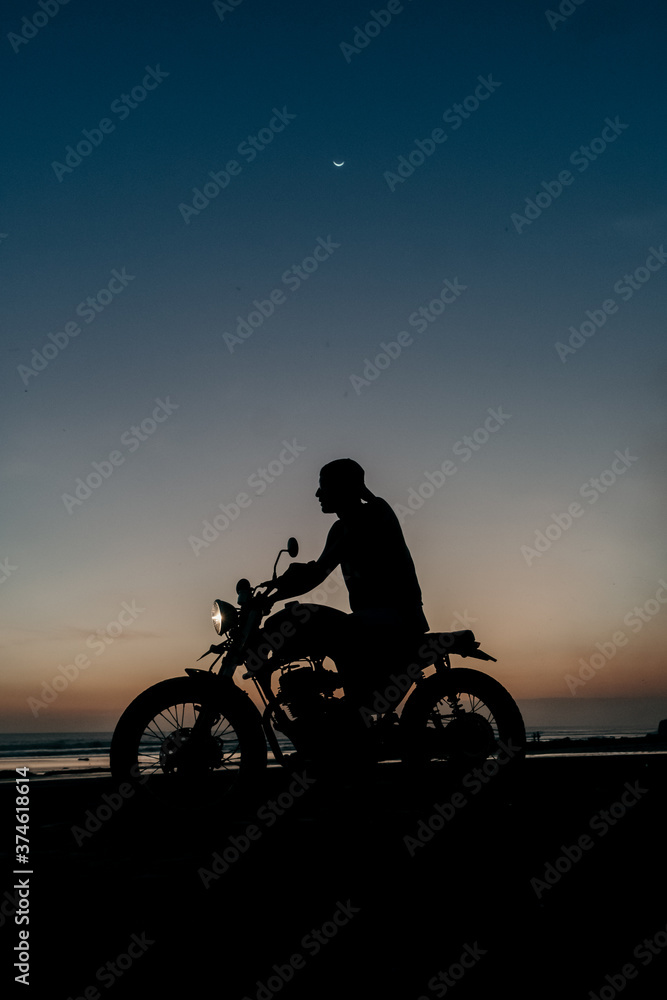 Obraz premium Male model on a custom bike during sunset in the beach