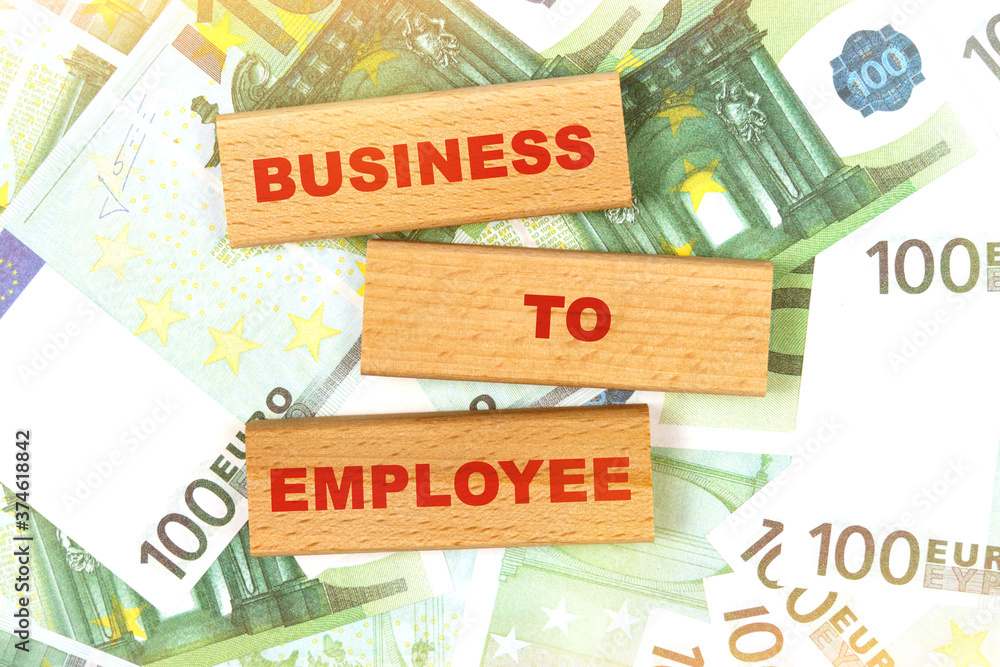 Against the background of euro bills, the text is written on wooden blocks - business to employee Against the background of euro bills, the text is written on wooden blocks - business to employee