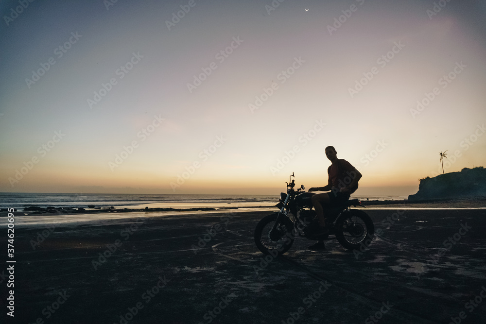 Obraz premium Male model on a custom bike during sunset in the beach