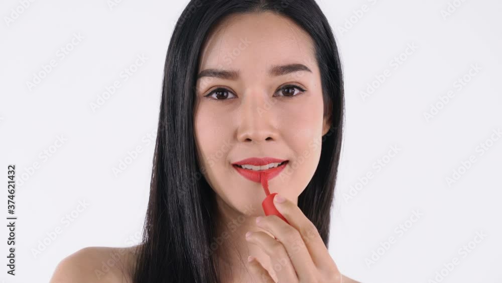 Young woman applying putting on some makeup using lipstick to color hel lips Young woman applying putting on some makeup using lipstick to color hel lips