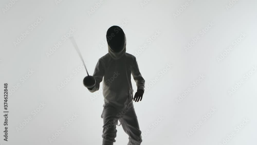 Dark silhouette of fencer training fencing exercise in studio indoors. Athlete is practicing an attack on an opponent. Shot isolated on white background. Slow motion. Close up. Dark silhouette of fencer training fencing exercise in studio indoors. Athlete is practicing an attack on an opponent. Shot isolated on white background. Slow motion. Close up.