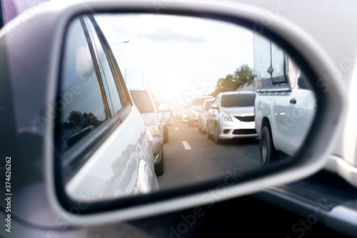 Fototapeta Naklejka Na Ścianę i Meble -  Abstract and blurred view from the side mirror of traffic congestion. Rear view of cars parked in long queues.  