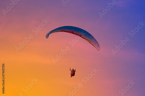 Paraglider flying on the res sky in sunset time in summer day. Cloud clear background.