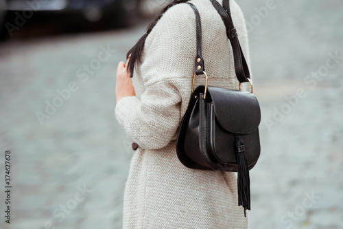 Photography Fashionable young woman in black jeans, beige cardigan and black handbag
