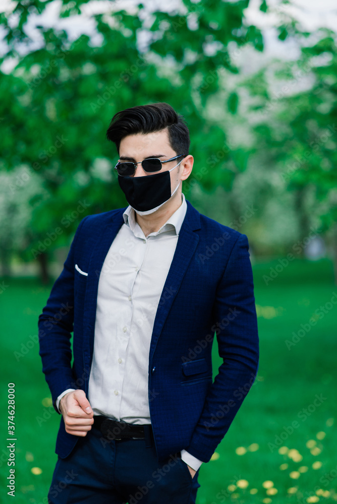 Groom in medical mask before wedding ceremony in the park outdoors. Weddings during the period of quarantine and pandemic of coronavirus infection Groom in medical mask before wedding ceremony in the park outdoors. Weddings during the period of quarantine and pandemic of coronavirus infection