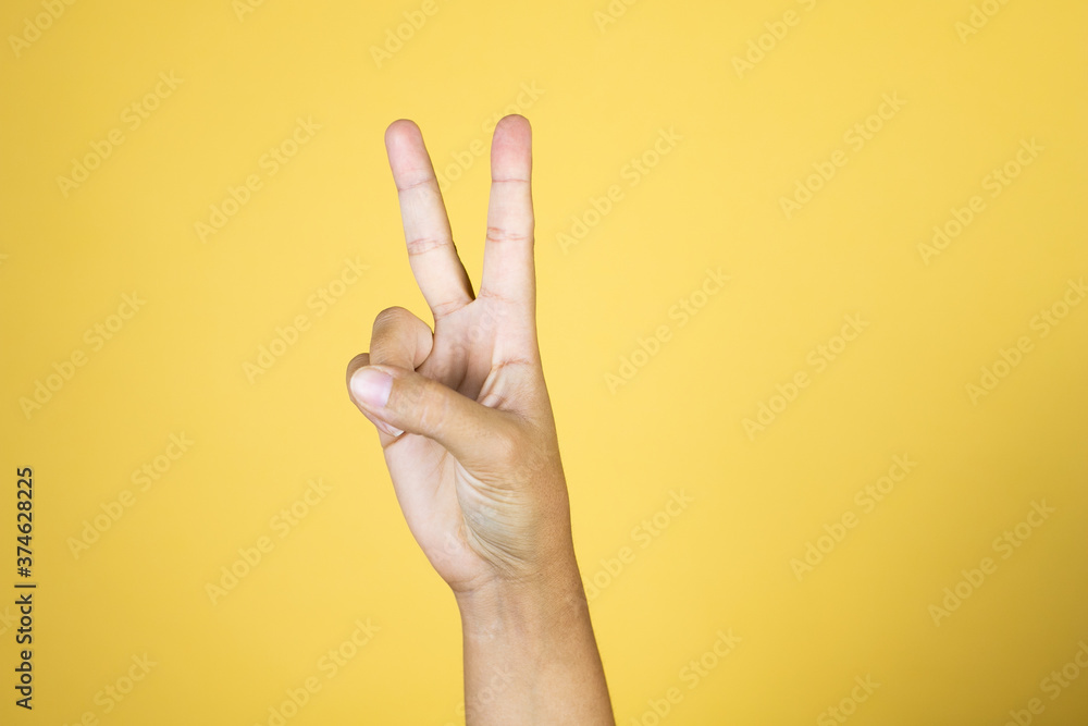Naklejka premium Hand over isolated yellow background showing with fingers number two or peace signal