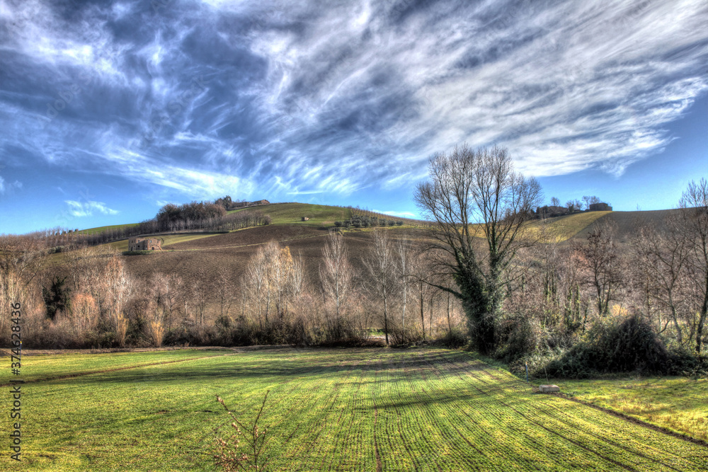 HDR autumn landscape on the Apennine mountains in Italy with cultivated countryside and sky full of beautiful clouds, in the background some badlands