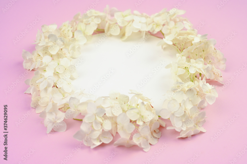 White petals frame on pink table. Side view