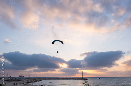 Motorized paraglider in amazing sunset sky above Ashkelon`s Marina