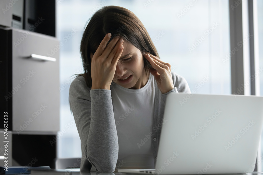 Unhappy stressed businesswoman touching head, exhausted unhealthy young woman employee worker suffering from migraine, strong headache, feeling pain, sitting at desk in modern office Unhappy stressed businesswoman touching head, exhausted unhealthy young woman employee worker suffering from migraine, strong headache, feeling pain, sitting at desk in modern office