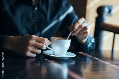 Cup of coffee on the table with white rice and a teaspoon of cafe mens hands.