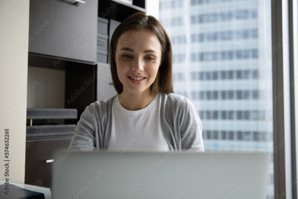 Smiling young businesswoman employee looking at laptop screen, working online, sitting at desk in modern office, woman worker intern reading good news in email, chatting in social network Smiling young businesswoman employee looking at laptop screen, working online, sitting at desk in modern office, woman worker intern reading good news in email, chatting in social network