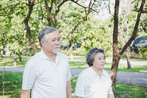 Old couple walking in a park together. Grandfather and grandmother get touchy each other after elderly couple had argument. Husband and wife get stressed and ignore each other, They get unhappy