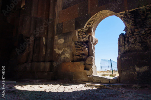 Eastern gates of Cathedral of Ani, medieval city Ani, near Kars, Turkey. There are shown interiors with damaged walls & remains of ornaments. Shiny bright day is outside the building © Poliorketes
