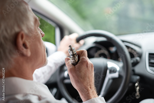 Man smoking an e-cigarette in car