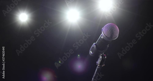 Camera in motion around concert microphone. Professional microphone on stage for record or speak to audience in dark in the spotlight. Musical instrument concept, vocal equipment.